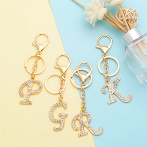 Close-up of golden alphabet P G R K keychains with rhinestones on colorful background