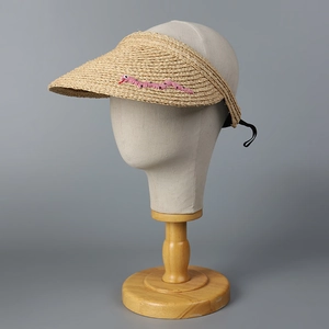 Detail der Raffia-Sonnenblende mit rosa Stickerei auf natürlichem Strohgewebe