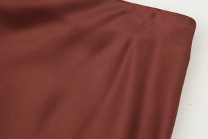 Detailed close-up of soft reddish-brown satin fabric showing fine texture and natural draping