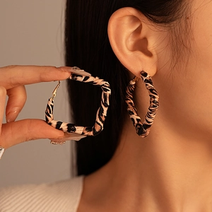 Bohemian large leopard print faux leather hoop earrings worn by a model in warm light