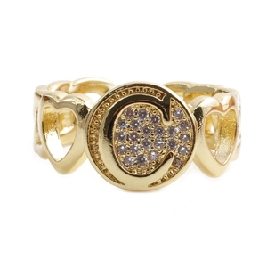 Macro detail of gold-plated heart ring featuring a crystal-encrusted C logo design