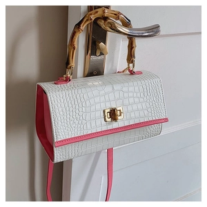 Close-up of white crocodile pattern bag with bamboo handle and gold bamboo lock