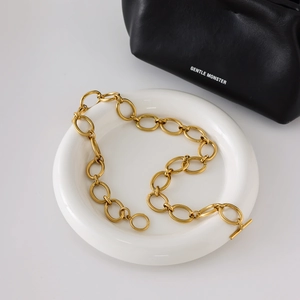 Collier à maillons géométriques dorés avec fermoir en T sur plateau d'exposition