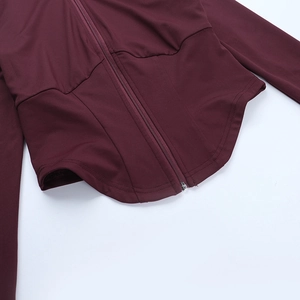 Detail of the curved hem and zipper on this slim-fit deep red yoga jacket