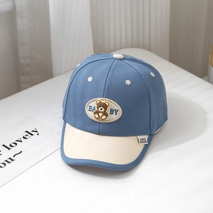 Close-up of baby baseball cap featuring blue contrast trim and brown bear patch embroidery