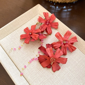 Detail of red fabric flower earrings with crystal tassels in a beige jewelry display box