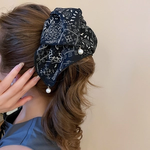 Detail of fabric hair tie with paisley print and elegant white pearl pendants