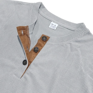 Detail eines grauen Herren-Henley-Shirts mit Rippstrickstruktur und brauner Wildlederleiste