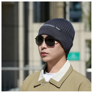 Close-up of dark blue ribbed knit beanie with small brand tag and gray decorative line