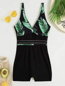 Detail of leaf print one-piece swimsuit with deep V-neck and hollow waist on beach setup