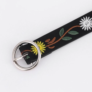 Close-up of black leather belt with yellow daisy embroidery and silver metal buckle