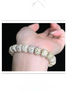 Close-up of creamy white Bodhi seed prayer beads bracelet worn on hand against black backdrop