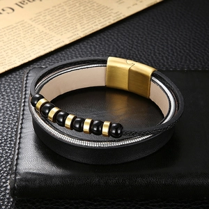 Detail of men's multilayer black leather bracelet with golden magnetic clasp and beads