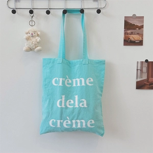 Detailansicht der mintgrünen Canvas-Tasche mit weißem creme de la creme Textaufdruck