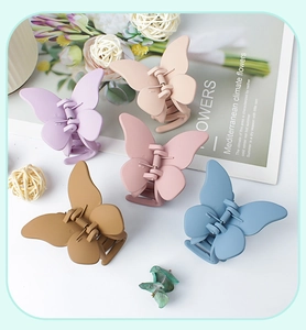 Flat lay of five matte butterfly hair claws in purple, beige, pink, brown and blue colors
