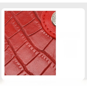 Close-up of red crocodile embossed leather with scratch-resistant surface and red stitching