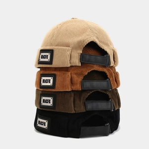 Pile verticale de bonnets docker en velours côtelé en quatre couleurs avec lanière cuir