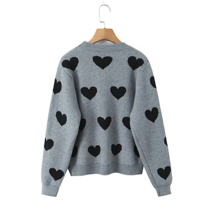 Detail of grey crewneck sweater with black heart jacquard pattern and ribbed cuffs