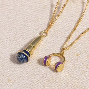 Close-up of golden microphone and headphone pendants with colorful enamel on a beige cloth