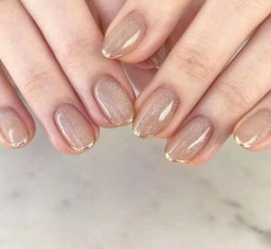 Detailed view of 3D cat-eye press-on nails with shimmering nude pink and gold french tips