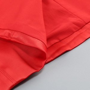 Close-up of fine stitching and fabric texture on a red satin evening dress shoulder