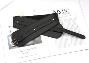 Detail of a black faux leather corset belt featuring gold rivets and a classic pin buckle