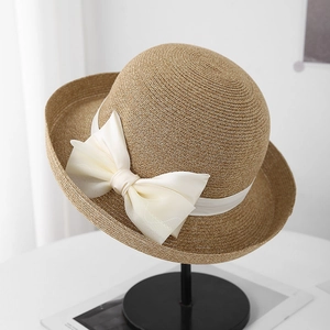 Detail van lichtbruine strooien hoed met een grote ivoren chiffon strik op zwarte standaard