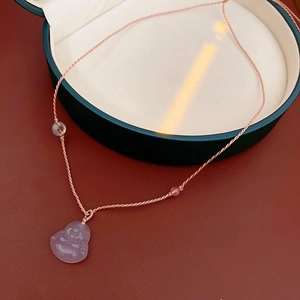 Macro shot of pink chalcedony Buddha pendant with woven cord in premium green gift box