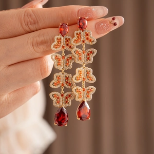 Détail de boucles d'oreilles vintage en or avec zircons rouges et motifs papillon