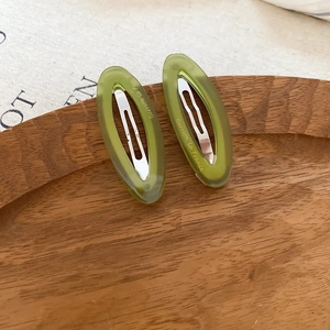 Detailed macro view of two green oval acetate hair clips with metal duckbill spring clips