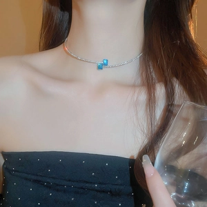 Close-up of elegant silver necklace with blue square zircons on model's neckline