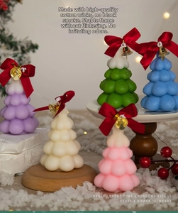 Detail view of five colorful Christmas tree candles with silk bows and golden bells