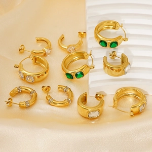 Détails macro de boucles d'oreilles en C dorées avec émeraudes et zircons
