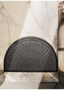 Detailed view of semi-circular dark grey door mat with textured fan pattern on floor