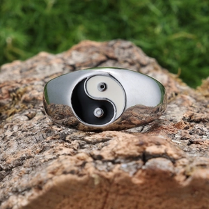 Polished stainless steel Yin Yang Tai Chi ring displayed on a natural textured bark background