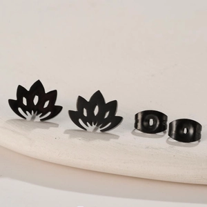 Detail of matte black lotus stud earrings with hollow design on stone texture base