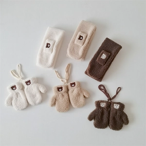 Flat lay of soft fleece baby mittens and headbands with cute bear embroidery details