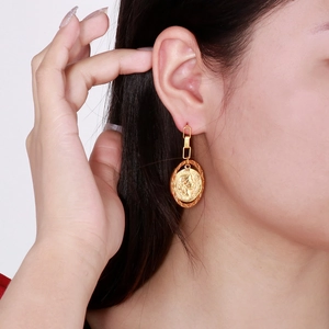 Detailed view of a model wearing a vintage gold coin portrait pendant earring in titanium steel