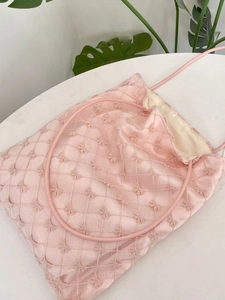 Sac fourre-tout rose avec broderie nœud et texture matelassée sur fond marbre