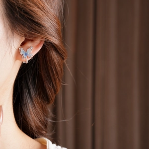 Macro detail of butterfly clip-on earring with sparkling blue zircons and 18k gold plating