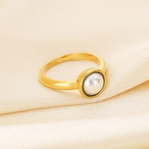 Detail eines einzelnen weißen Perle in poliertem Gold-Edelstahlring auf Champagner-Seide