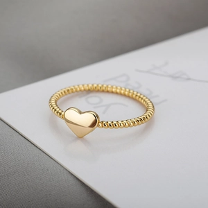 Polished 18k gold heart ring with a twisted rope band design on minimalist background