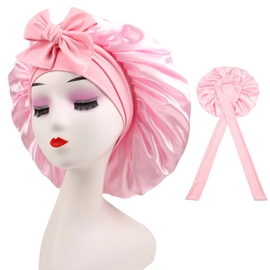 Detailed view of pink satin sleeping cap featuring an elegant bow and long ribbons