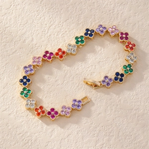 Macro view of gold bracelet with colorful cubic zirconia in clover charms