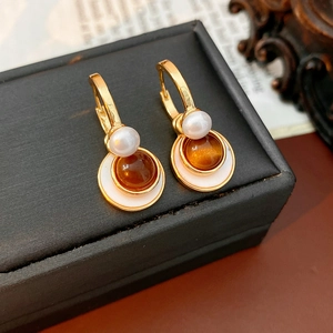 Macro view of gold vintage earrings with tiger eye stone and white pearl detail