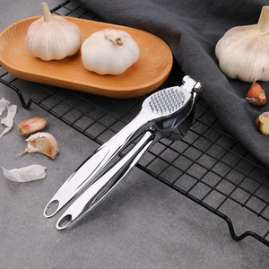Close-up of a silver zinc alloy garlic press on a rustic wooden tray in a kitchen setting