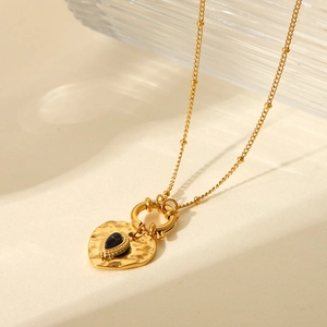 Detail of vintage heart pendant with black gemstone and gold hammer texture necklace