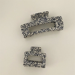 Detail view of large and small spotted square hair claws in ivory and black