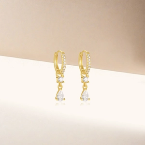 Detail of gold teardrop earrings featuring clear zircon stones and shimmering accents