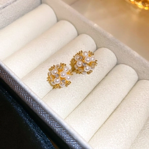 Macro shot of elegant gold floral earrings with pearls and zircons in a velvet jewelry box